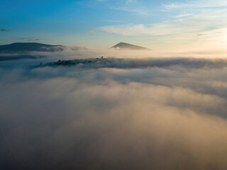 The rays of dawn over the fog in the Ukrainian Carpathians. Aerial drone view.