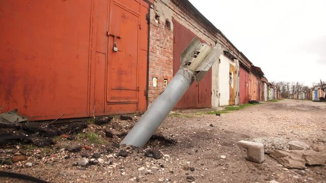 Close-up view 4k video footage of real unexploded military missile, torpedo or shell stuck in ground near doors of garages outdoors. Moments of dreadful war of Russia against Ukraine in 2022