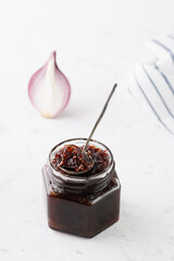 onion marmalade (Onion confiture). onion confit in a glass jar on a white background.