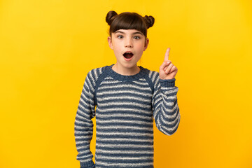 Little caucasian girl isolated on yellow background intending to realizes the solution while lifting a finger up