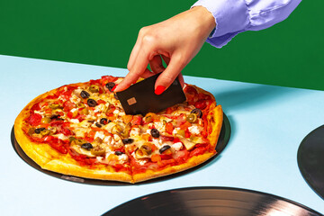 Creative slicing pizza. Female hands with italian pizza lying on vinyl discs on light tablecloth isolated on green background. Vintage, retro style fashion, music