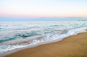 Summer evening at the seashore. View of the soft sea wave on the sandy beach.