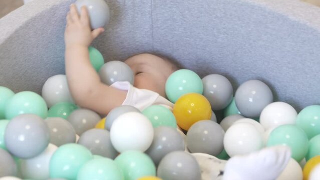 Kid playing in ball pit at home. Happy kid in soft ball pit pool with colorful balls for toddlers, caucasian baby boy having fun playing at home. . High quality 4k footage