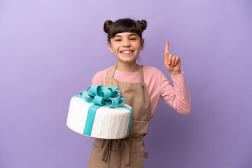Pastry little girl holding a big cake isolated on purple background pointing up a great idea