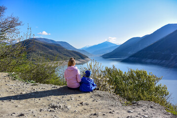 Fototapeta premium A young girl and a little boy on the background of the landscape of the Zhinvali reservoir. Georgia 2019.