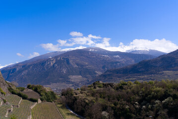 Aerial view from hill of City of Sion over the beautiful landscape of Canton Valais with the Swiss Alps on a blue cloudy spring day. Photo taken April 4th, 2022, Sion, Switzerland.