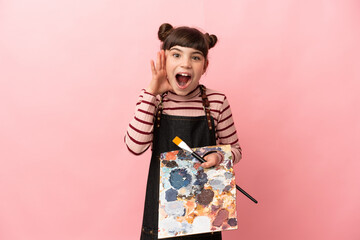 Little artist girl holding a palette isolated on pink background with surprise and shocked facial expression