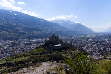 Fototapeta premium Aerial view with beautiful medieval catholic church and castle Basilique de Valère (Valeria) on a hill at City of Sion on a sunny spring day. Photo taken April 4th, 2022, Sion, Switzerland.