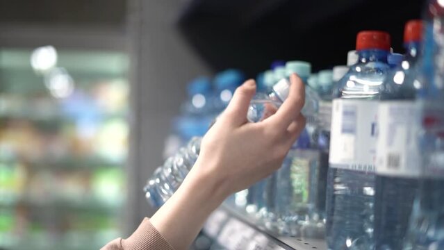 A girl chooses drinking water in a store.