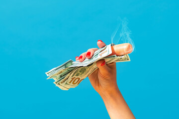 Food pop art photography. Female hand holding hot sausage wrapped in banknotes isolated on bright...