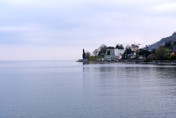 Naklejka premium Lakeshore with riviera at City of Vevey with Lake Geneva on cloudy spring day. Photo taken April 4th, 2022, Vevey, Switzerland.