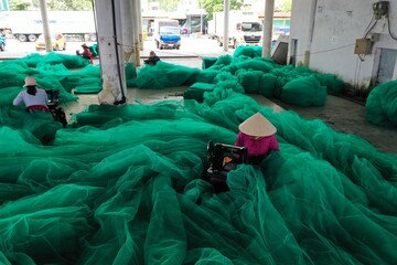 Workers are repairing fishing nets to prepare to go out to sea