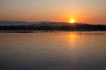 Naklejka premium dramatic morning sky from the shore of Lake and rich sunny light