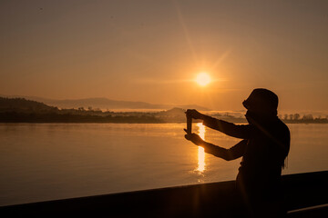 Silhouette of a woman taking a picture in the midst of a beautiful sunset or sunrise