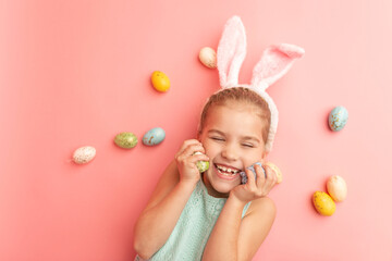 Obraz na płótnie Canvas Portrait of cute smiling girl with Bunny ears and colorful Easter eggs isolated on pink background. Happy Easter