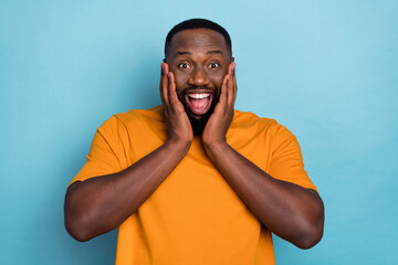 Photo of funky shocked guy dressed orange t-shirt smiling arms cheeks isolated blue color background
