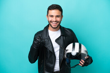 Young Brazilian woman with a motorcycle helmet isolated on blue background celebrating a victory in winner position - obrazy, fototapety, plakaty