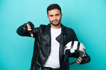 Young Brazilian woman with a motorcycle helmet isolated on blue background showing thumb down with negative expression