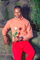 Young African American Man holding white flower, waiting for you at park in New York