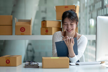 Starting Small business entrepreneur freelance,Portrait young woman working at home office, BOX,smartphone,laptop, online, marketing, packaging, delivery, SME, e-commerce concept