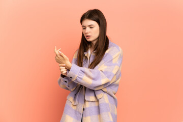 Young Ukrainian girl isolated on pink background suffering from pain in hands