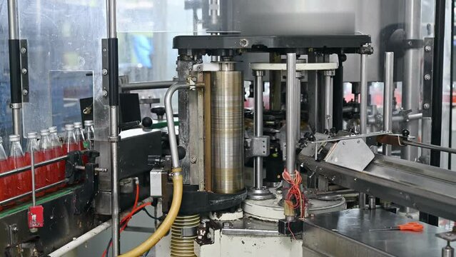 Automatic product labeling machinery working with red juice in production line at bottling factory