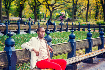 Young African American Man sitting on bench, relaxing in Central Park, New York