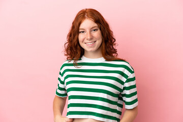 Teenager redhead girl over isolated pink background laughing