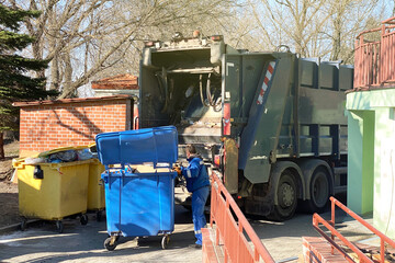 a large garbage truck collects garbage from bins on a city street, garbage disposal
