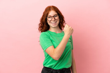 Teenager redhead girl over isolated pink background celebrating a victory