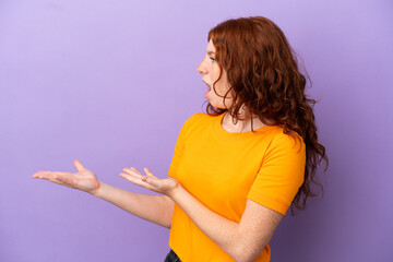 Teenager redhead girl over isolated purple background with surprise expression while looking side