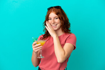 Teenager redhead girl holding cocktail isolated on blue background whispering something - obrazy, fototapety, plakaty