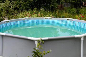 Grey frame swimming pool on the green lawn with trees