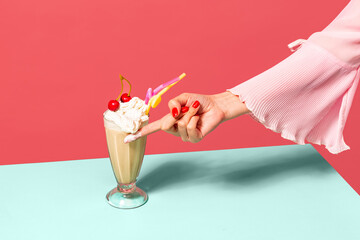 Coffee and whipped cream. Female hand touching high glass with irish coffee isolated on light pink background. Trendy colors. Pop art, retro style.
