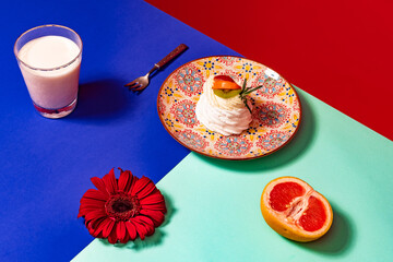 Served table. Food pop art photography. Glass of milk, cake and flower on blue and turquoise color tablecloth over red background. Vintage, retro style interior