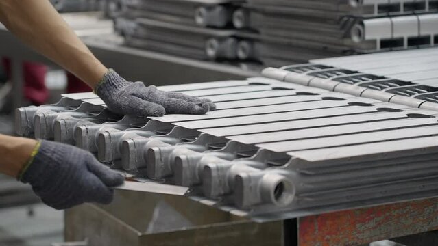 The worker processes the radiator part, removes the burr after casting, prepares it for further processing. Production of household radiators at the radiator manufacturing plant.
