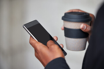 Checking emails first thing in the morning. Shot of an unrecognizable businessman using a phone in the city.
