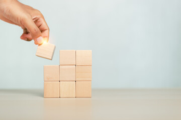 concept of grow success. hand holding and stacking wooden block cube step of business growth...