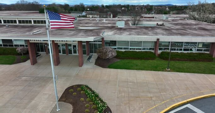 Aerial shot the entrance of an elementary school in Pennsylvania with  a close view to the American USA flag.