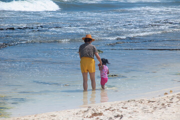 Rearview of a mature Latina woman holding hands with her granddaughter in the Caribbean Sea in Mexico
