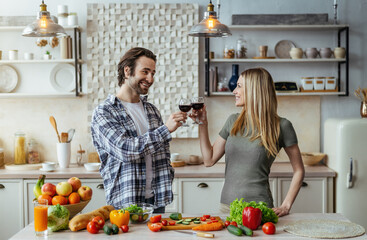 Happy millennial caucasian husband with stubble and wife cooking dinner with organic vegetables