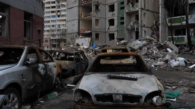 Chernihiv Ukraine 2022: Burnt destroyed civilian cars against the background of  destroyed building as a result of an air attack. Result of rocket or artillery shelling by Russian Federation army. War
