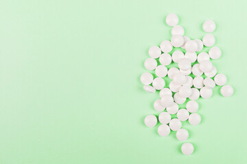 White pills on a pastel green background. Flat lay, top view, overhead, mockup, template, copy space. Pharmacy and medical concept