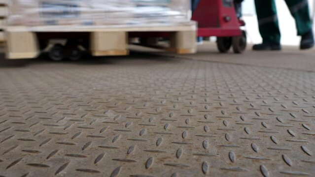 Loading goods on a forklift pallet truck in a retail or wholesale warehouse. Logistics of distribution of products or humanitarian aid. Moving loaded warehouse trolley. Shooting video from the ground.