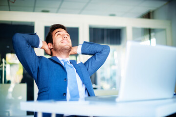 Fototapeta premium Cropped shot of relaxed businessman sitting at desk in office leaning back