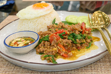 Stir fried Thai basil with minced pork and a fried egg on white plate