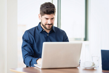 Fototapeta premium Businessman using his laptop while sitting at desk in the office