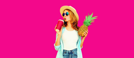 Summer portrait of beautiful woman drinking juice and holding pineapple wearing straw hat, sunglasses on pink background