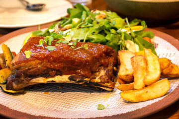 Pork ribs grilled with BBQ sauce served with french fries and vegetables.