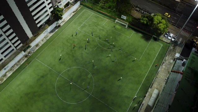 Soccer players play a friendly match on a field next to the street